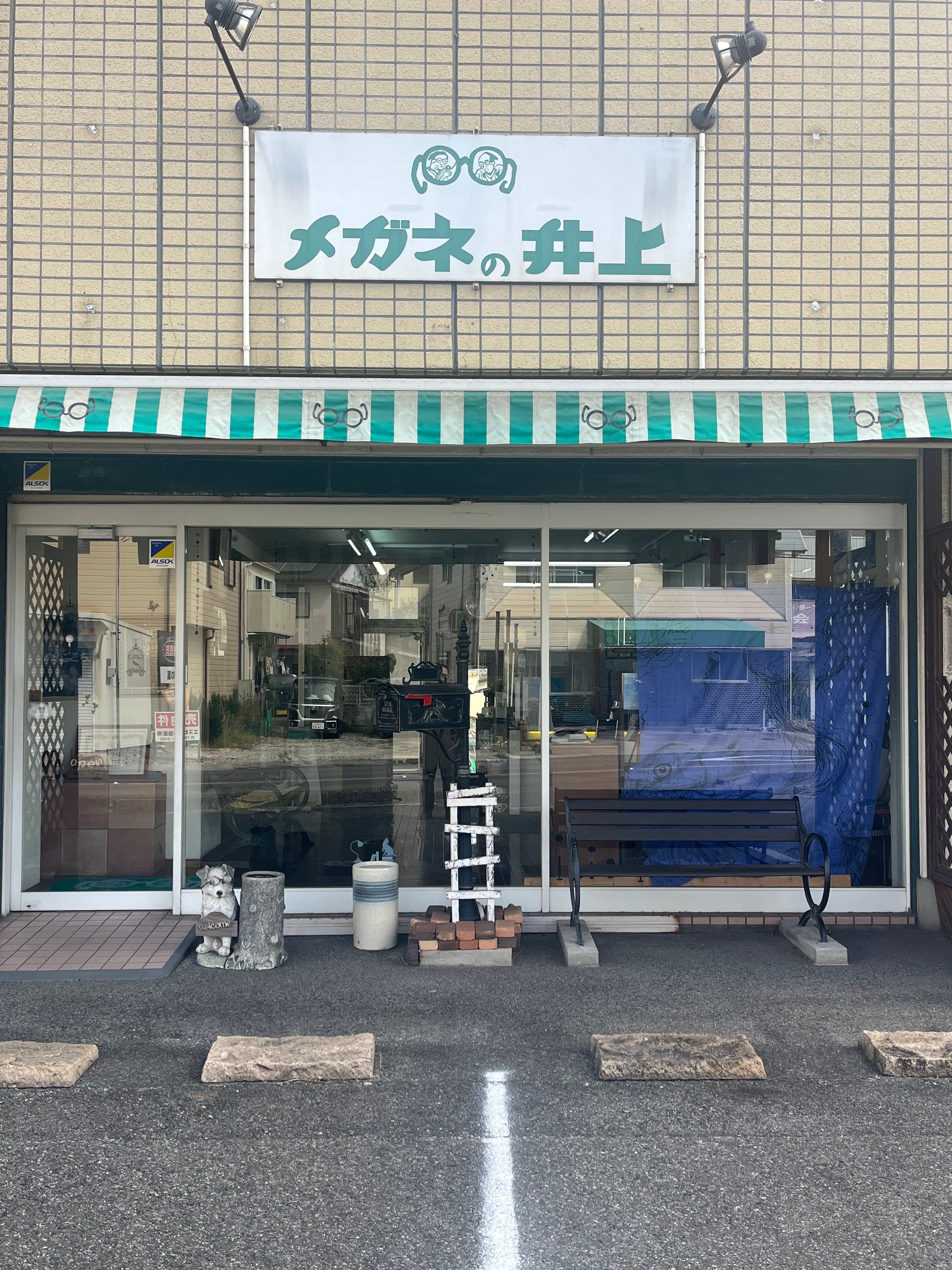「メガネの井上」の看板と緑の日よけが掛かる店舗の外観